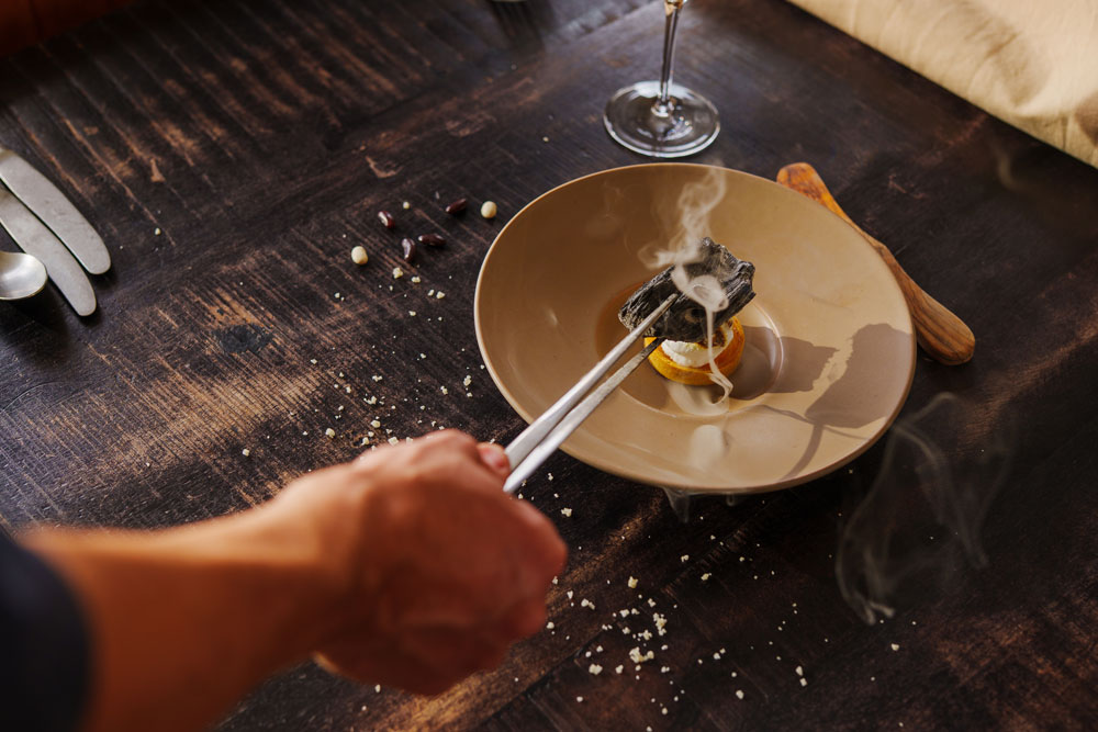 Chef bereidt een gerecht boven houtskool tijdens een culinaire workshop koken met vuur