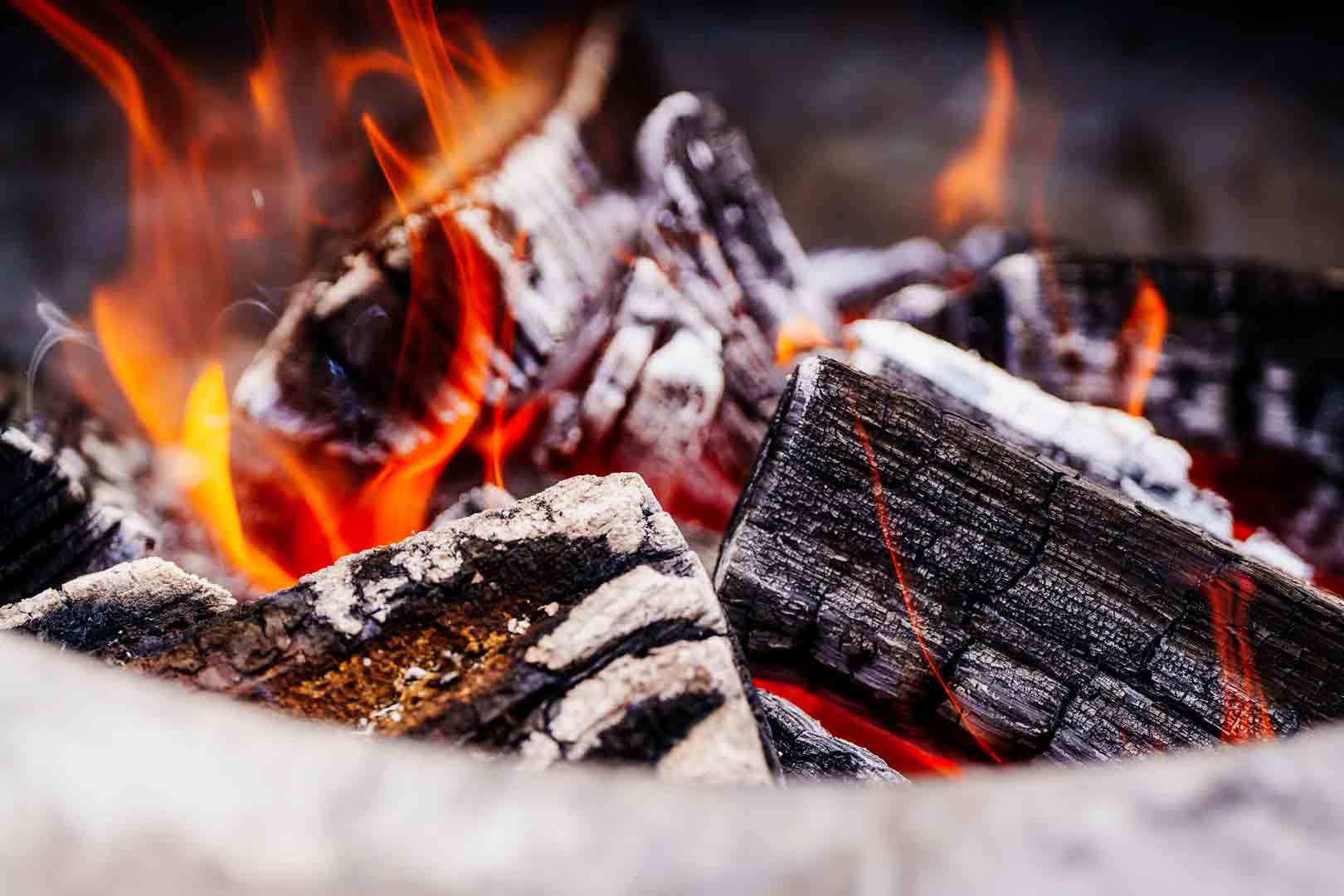 Gloeiende houtskool en vuur, symbool voor het ambachtelijke koken van Studio Smaeck met seizoensproducten en pure ingrediënten